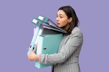 Beautiful young businesswoman with folders on lilac background