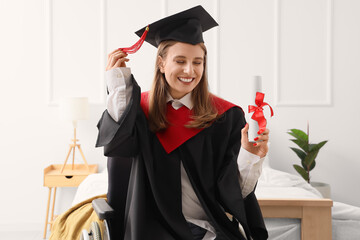 Happy female graduate in wheelchair with diploma at home