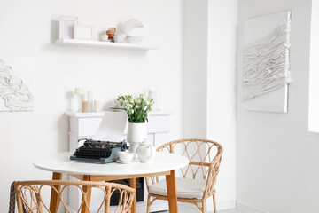 Vintage typewriter with teapot and flowers on table in dining room