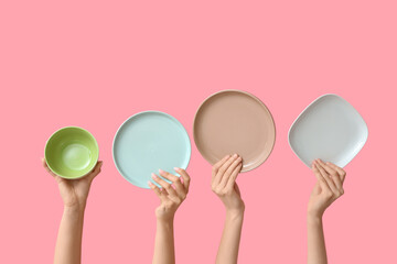 Hands holding empty plates on pink background
