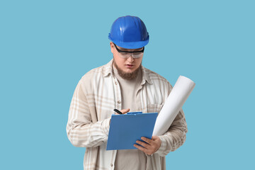 Young male engineer with clipboard and drawing on blue background