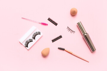 Different false eyelashes with brushes, mascara and sponges on pink background