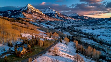 Panoramic aerial view of rugged snowy mountains at sunset, with golden light casting long shadows on the slopes  