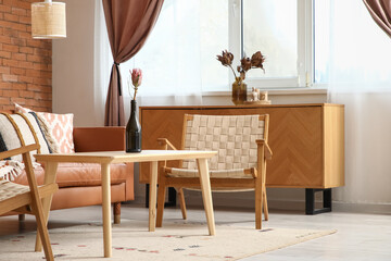 Cozy sofa, wicker armchair and coffee table in interior of living room