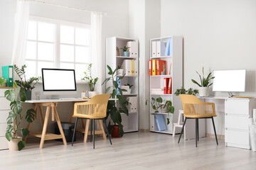 Interior of office with desks, shelf units and green houseplants