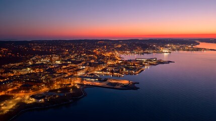 Fototapeta premium An aerial view of a city illuminated at dusk, showcasing a vibrant cityscape along a coastline.