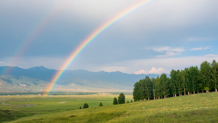 Realistic rainbow over a serene landscape with mountains and trees, digital painting with soft light effects
