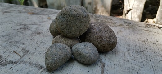 An oval natural rock resting on outdoor ground, highlighting unique shape, earthy texture, and...