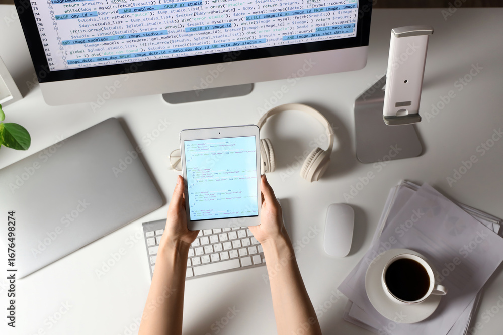 Poster female programmer's hands working with tablet computer at table, top view
