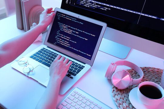 Female programmer's hands working with laptop at table in office, closeup