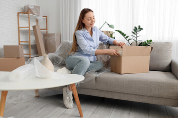 Young woman packing box in room on moving day