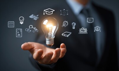 Businessman's hand holding illuminated lightbulb with various learning icons