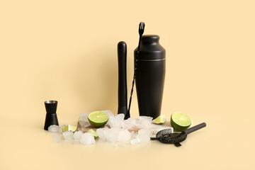 Different bartender utensils, ice cubes and lime on beige background