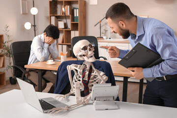 Angry businessman shouting at human skeleton in office