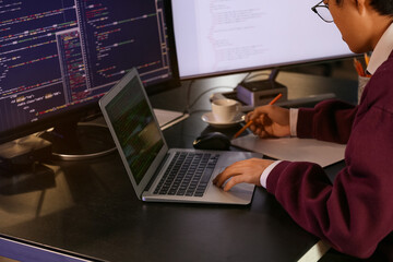 Male programmer working with laptop late in office, closeup