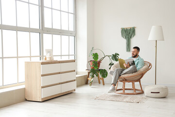 Handsome man reading magazine in cocoon chair at home