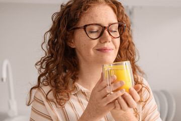 Young redhead woman with turmeric drink in kitchen, closeup