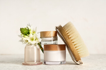 Vacuum jar with brush for anti-cellulite massage, cream and flower on white grunge table