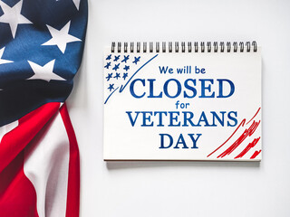 We will be closed for Veterans Day. American Flag and sign board with the inscription. Closeup, no people. Congratulations for family, relatives, friends, colleagues