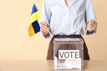 Voting woman with flag of Ukraine near ballot box on beige background