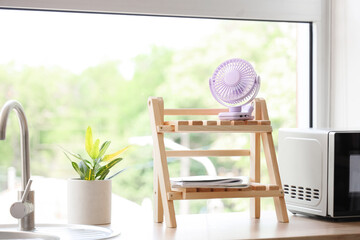 Lilac mini fan on shelf in kitchen