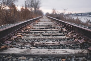 A weathered railway track extends into the distance on a cloudy day