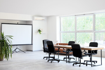 Interior of conference hall with table, plants and projector screen