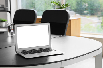 Blank laptop on table in conference hall, closeup