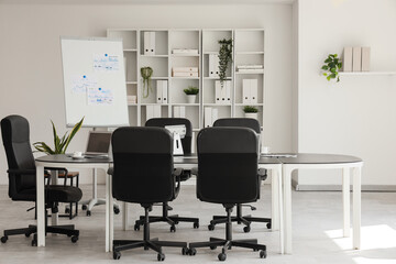 Interior of conference hall with table, flipchart and shelf unit