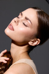 beauty woman with glowing skin and closed eyes poses gracefully against dark background, showcasing...