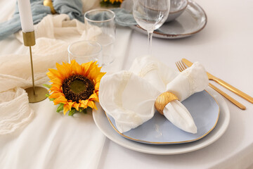 Elegant table serving with plate, folded napkin and beautiful sunflower, closeup