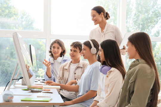 Female teacher conducting lesson to students at school computer lab