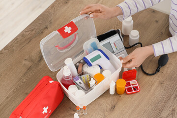 Young woman with first aid kits and medical supplies on table in kitchen