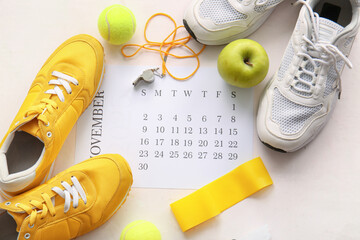 Composition with paper calendar, sports equipment and shoes on light background
