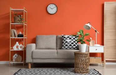 Interior of stylish living room with grey couch, tables and shelf unit
