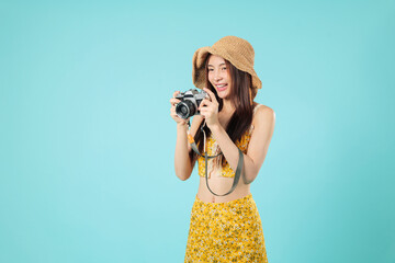 Happy young asian woman traveler holding a camera is reviewing the photo picture on the screen, and she looking forward to continuing her travel today, headshots isolated studio blue background