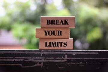 Motivational Quote 'Break Your Limits' On Wooden Blocks Outdoors with a blurred background