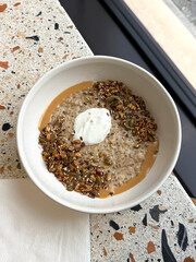 Oatmeal with baked granola, cream and peanut butter. Healthy breakfast and complex carbs concept. Handheld mobile photo, selective focus, non AI