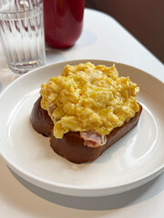 Breakfast sandwich topped with crispy bacon, fluffy scrambled eggs and truffle oil. Dining outside concept. Handheld mobile photo, selective focus, non AI