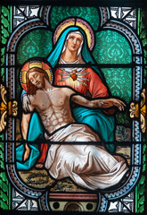 Fototapeta premium Stained glass (19th century) of Pieta (Madonna of Seven Sorrows). Blessed Virgin Mary holding Jesus Christ body after his Deposition from the Cross.