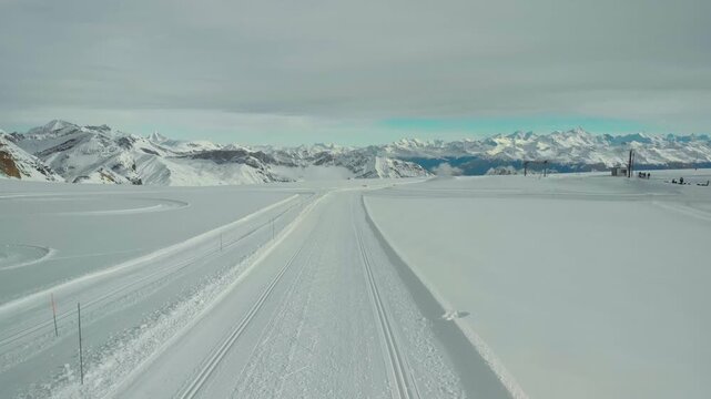 A breathtaking view of a snow-covered road winding through majestic mountains, dotted with patches of snow and stunning peaks in the background. A serene winter landscape perfect for outdoor adventure