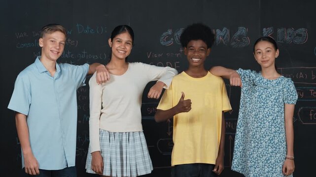 Diverse student pose at camera while african boy showing thump up. Multicultural teenager looking at camera while standing at black board with engineering code written at STEM class. Edification