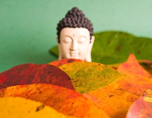 Buddha statue amidst autumn leaves