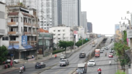 Blurred daytime view of Bangkok street with moving traffic and vehicles.
