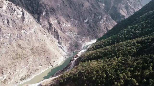 Aerial view of the Jinsha River flowing through a valley surrounded by mountains and lush forest in the Tiger Leaping Gorge, Yunnan, China