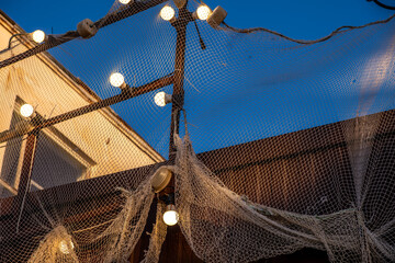 A fishing net hung with light bulbs on the street.