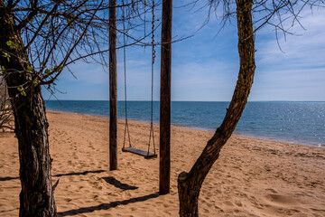 An empty swing on poles by the sea on a summer day.