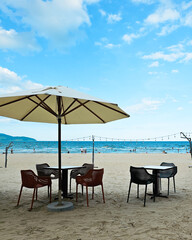 Beach umbrellas and chairs with ocean waves and blue sky at a tropical seaside.