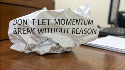 Crumpled paper note with inspirational quote on brown wooden desk