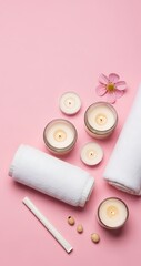 Top view of spa and wellness items with white rolled towels, lit candles, pink flower, and beauty product tube on a pastel pink background, ideal for relaxation.